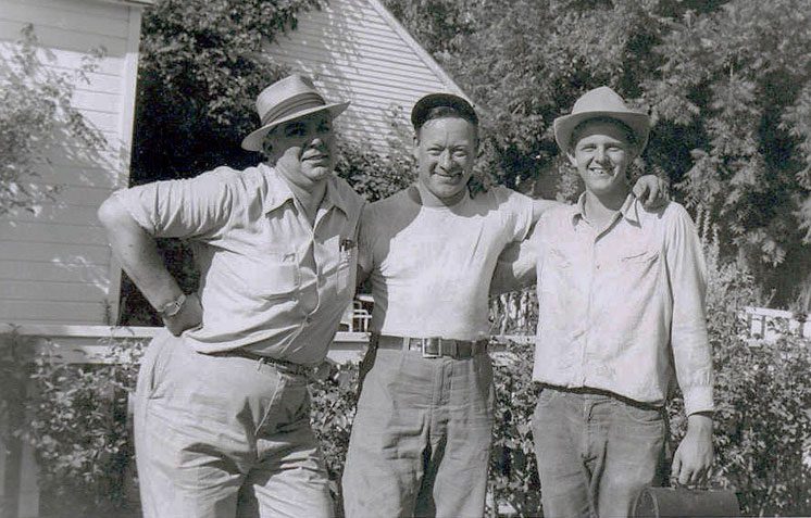 Three men standing next to each other in front of a building.