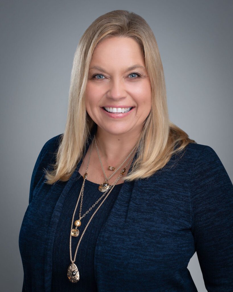 A woman with blond hair wearing a blue sweater.