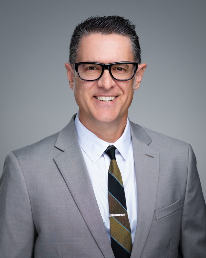 A man in a suit and tie smiling for the camera.