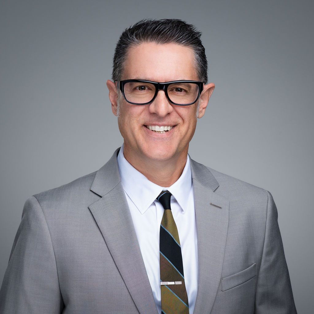 A man in a suit and tie smiling for the camera.