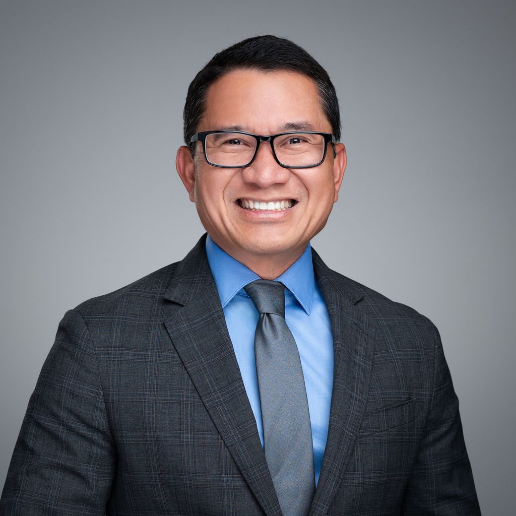 A man in a suit and tie smiling for the camera.