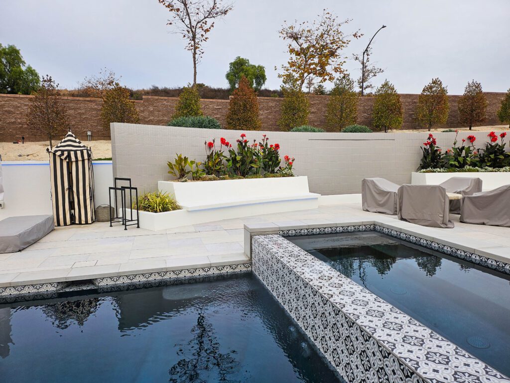 Modern backyard pool with spa and plants.