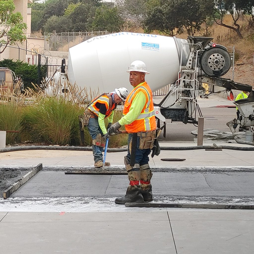 Construction workers pouring concrete near mixer truck.