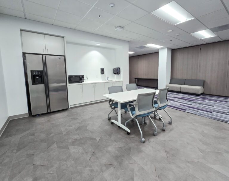Modern office kitchenette with table and chairs.