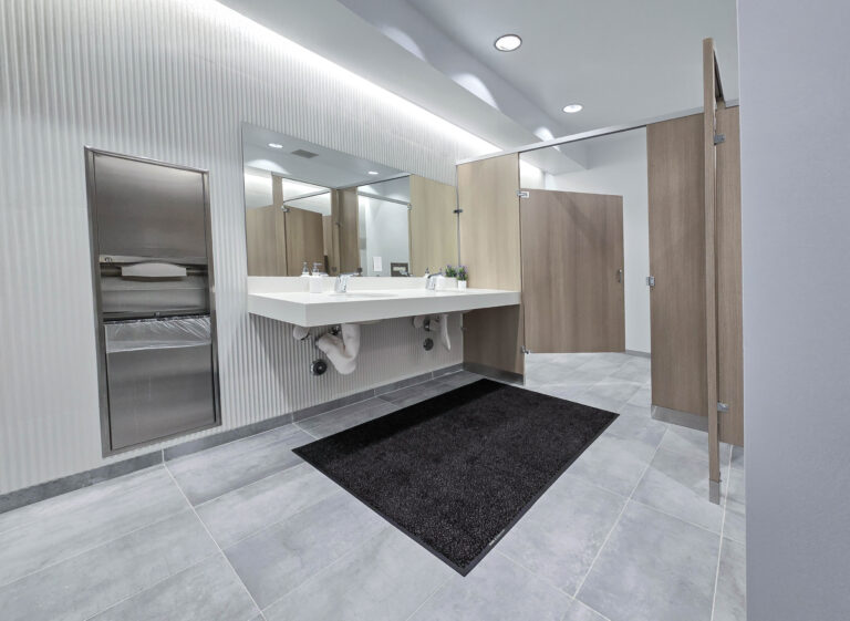 Modern restroom with sinks and wooden stalls.