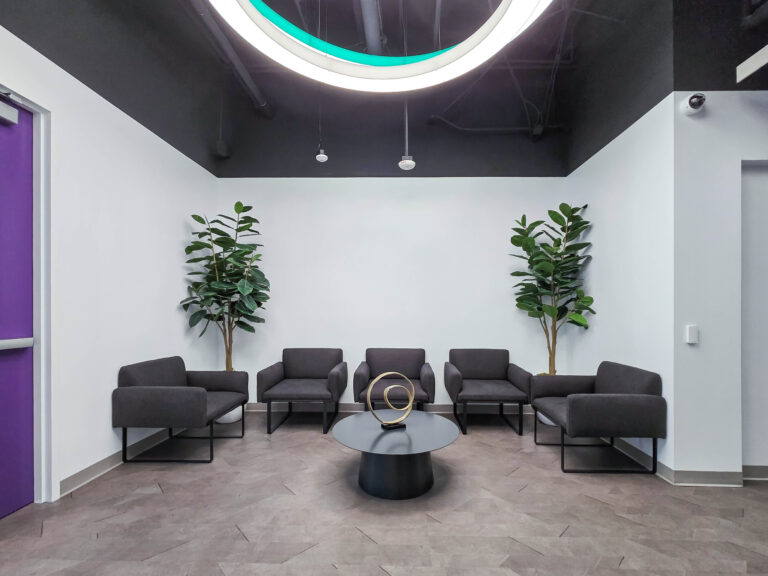 Modern office waiting area with black chairs.