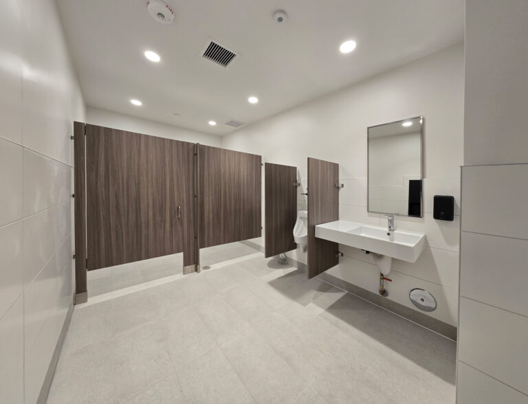 Bright restroom with sink and wood stalls